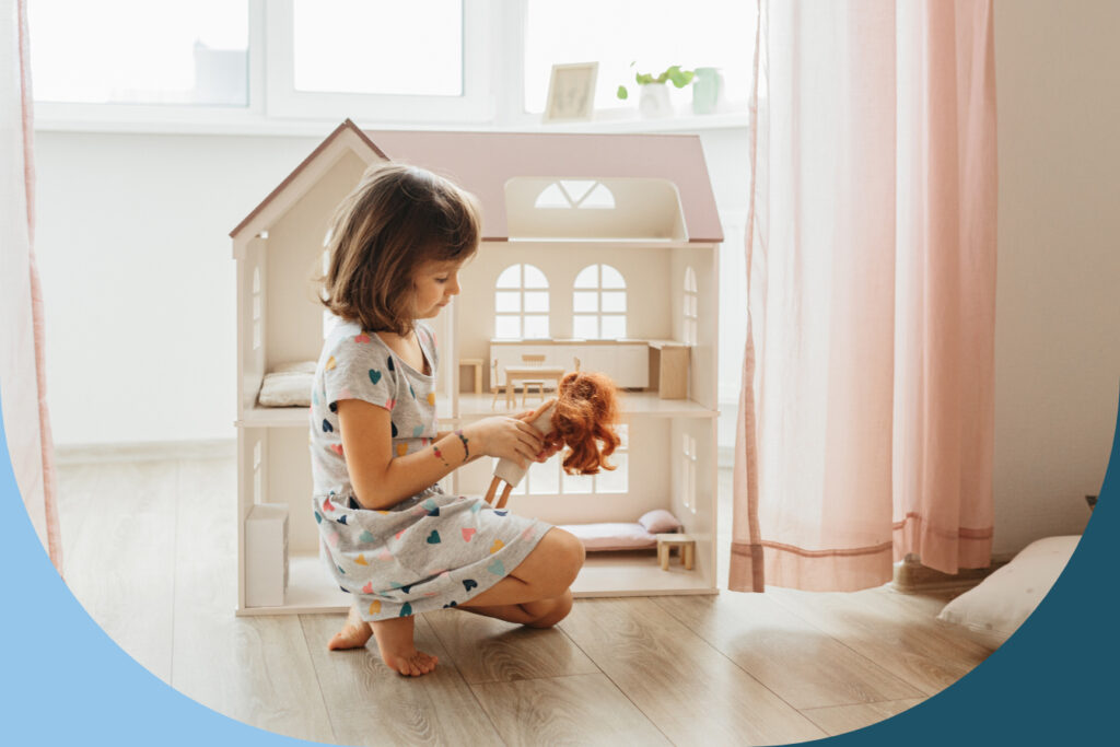 Girl sitting on floor, playing with her doll and dollhouse