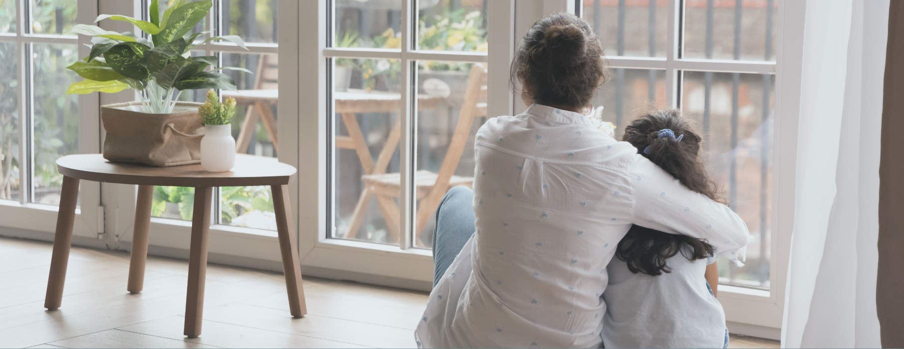 Mother sat on floor hugging daughter